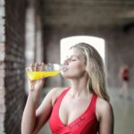 Athletic woman enjoying a refreshing drink in a gym environment, promoting fitness and hydration.