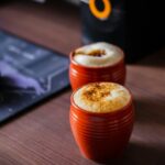 two orange cups sitting on top of a wooden table