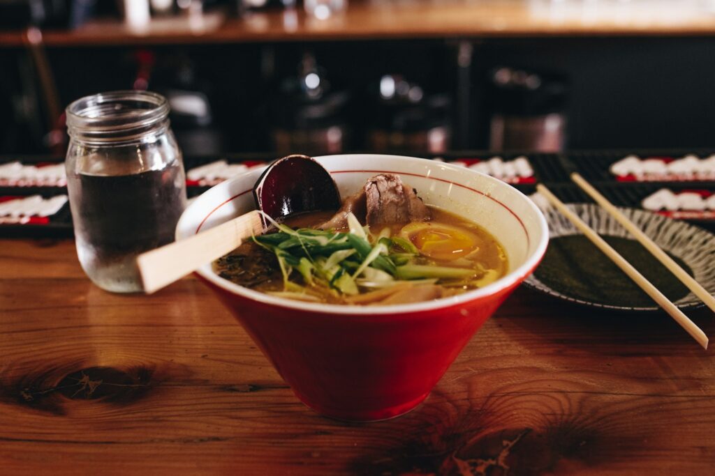 udon soup with vegetable beside chopsticks and glass of water